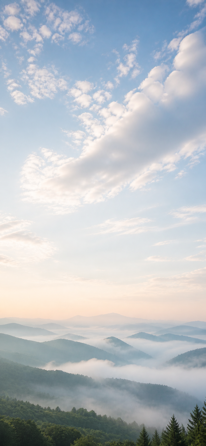 Misty mountains beneath a vast pale sky